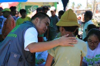 Oxfam staff Vincent Malasador gives support and reassurance to recipient during the distribution of hygiene items in northern Cebu.